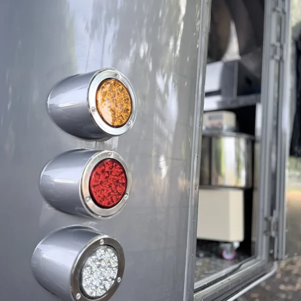 The rear lights of the Airstream, amber, red and white, beside the open door